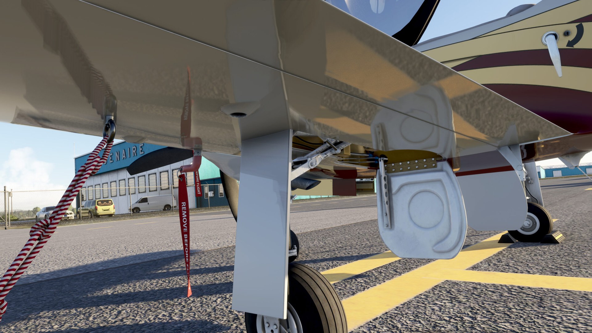 The underside of a Legacy RG550's wing, with the main landing gear and a red tie-down strap