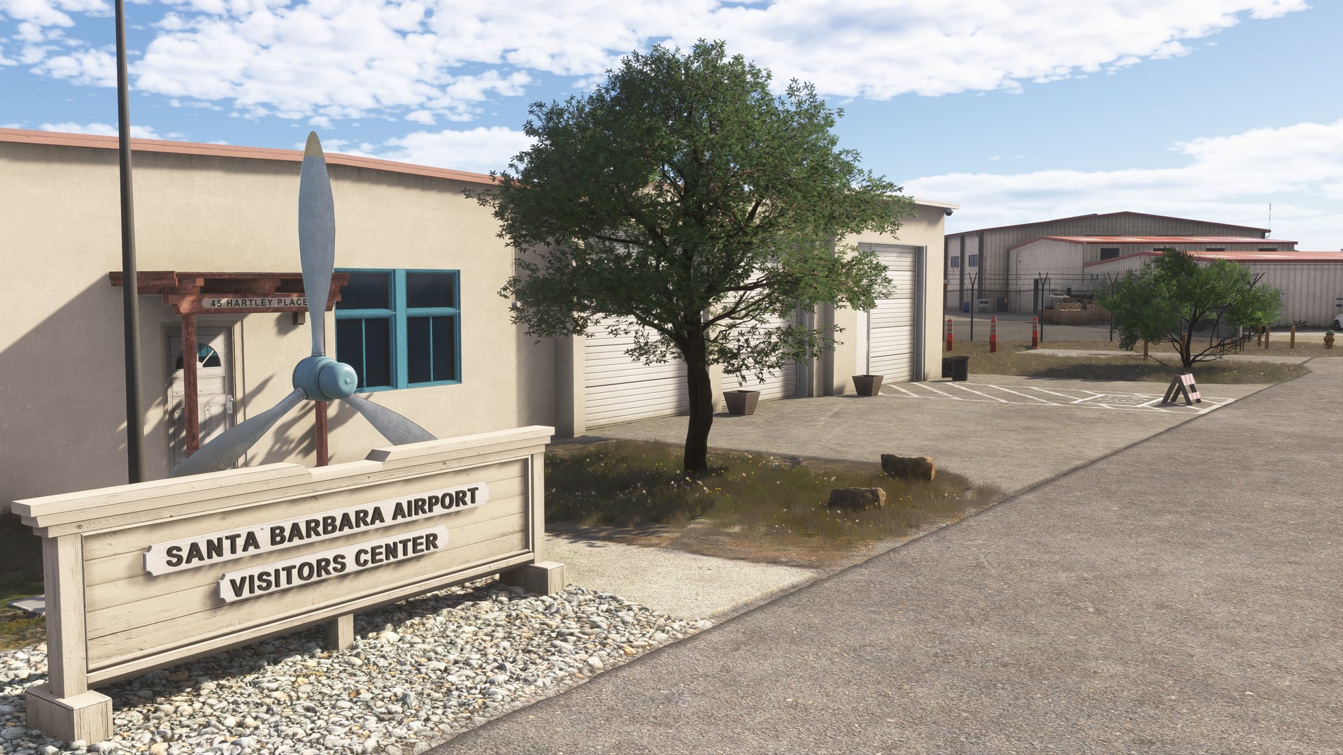 The "Santa Barbara Airport Visitors Center" sign in front of a building, with an aircraft monument behind