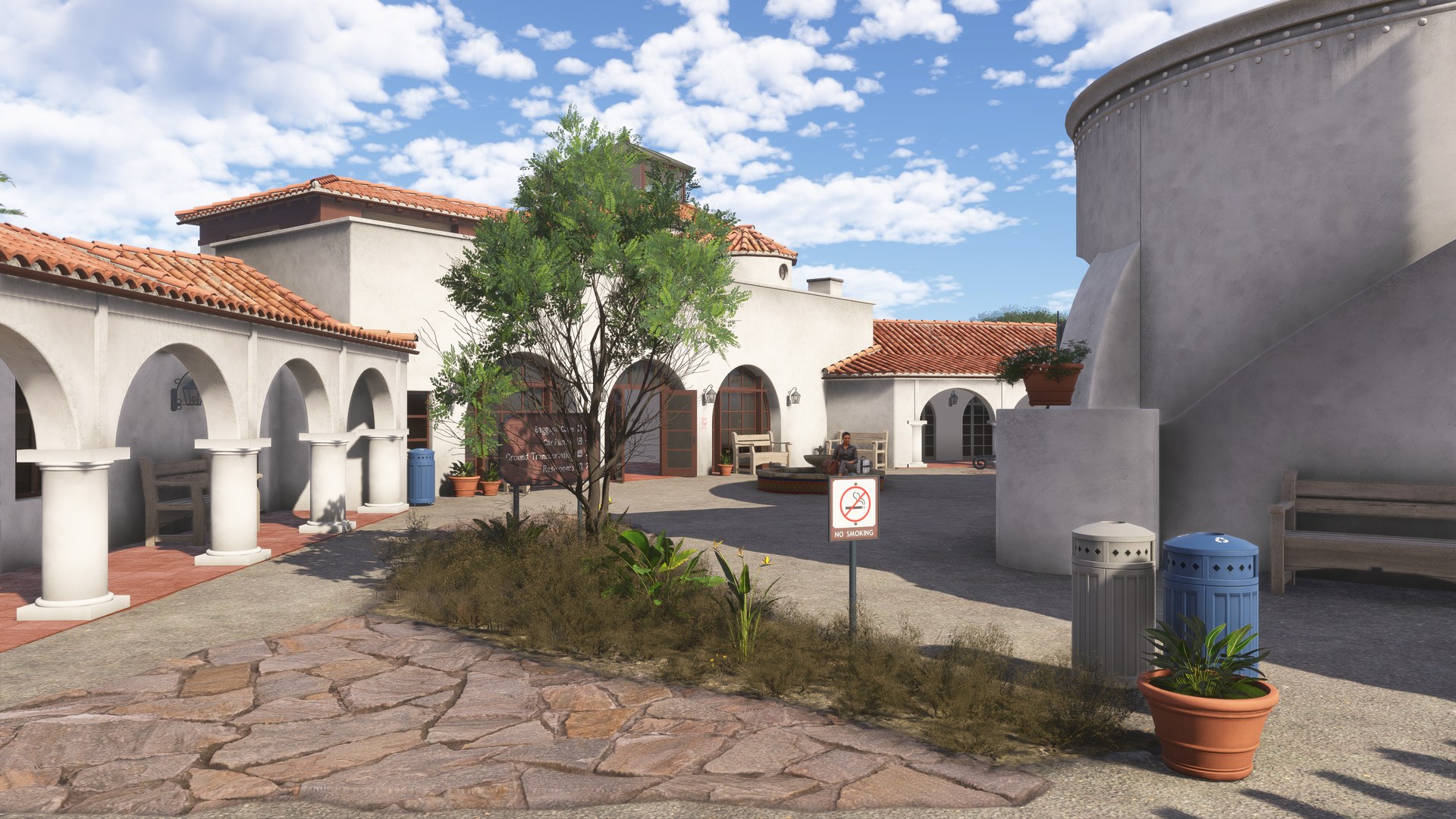 An arched walkway and a landscaped courtyard with a tree outside the terminal
