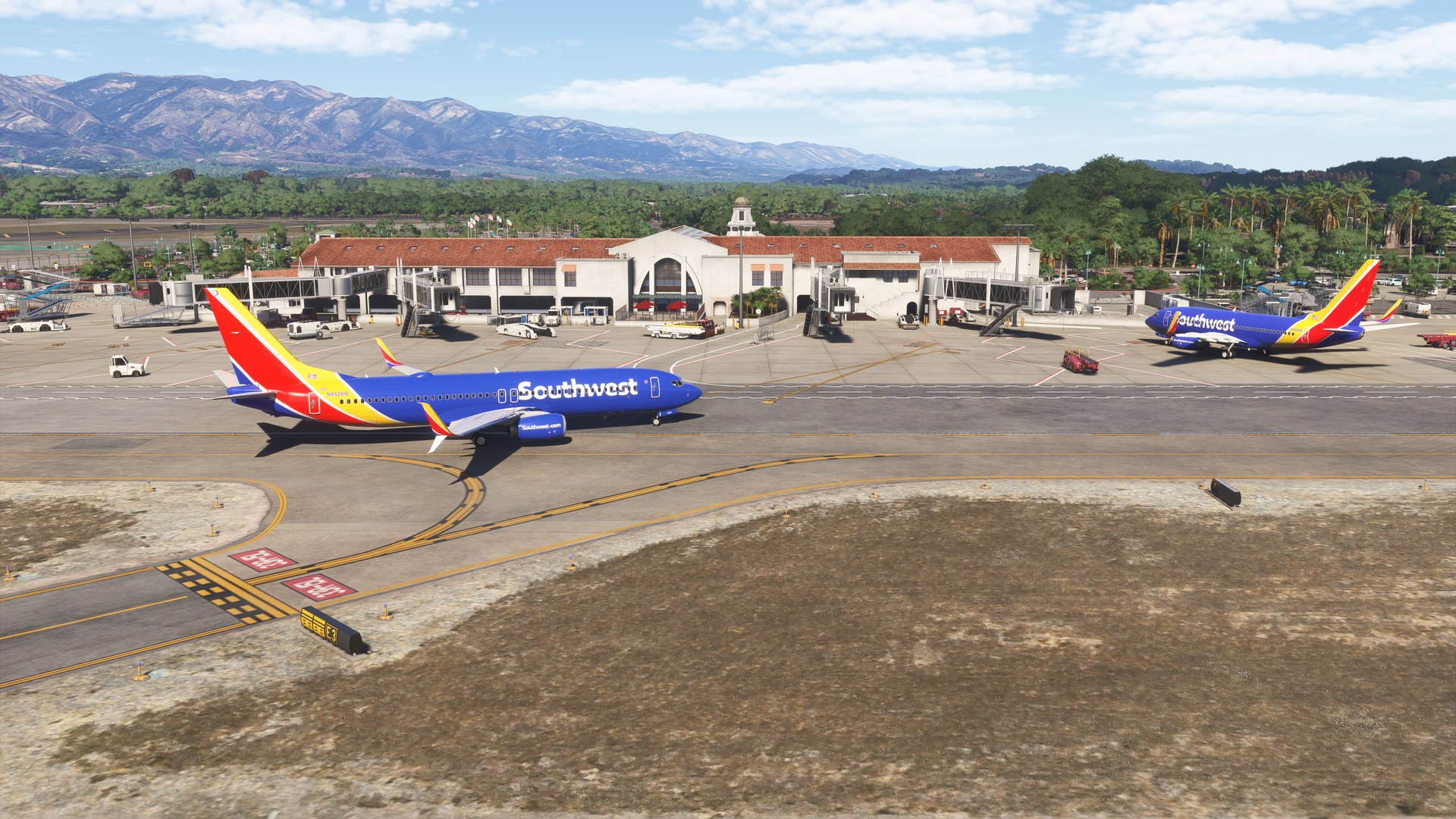A Southwest Airlines Boeing 737 taxiing past the terminal, with mountains in the background